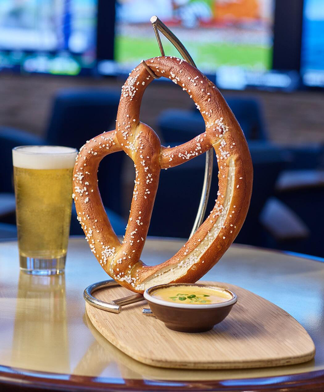 large pretzel with cheese and a pint glass of beer at the lounge with caesars sports