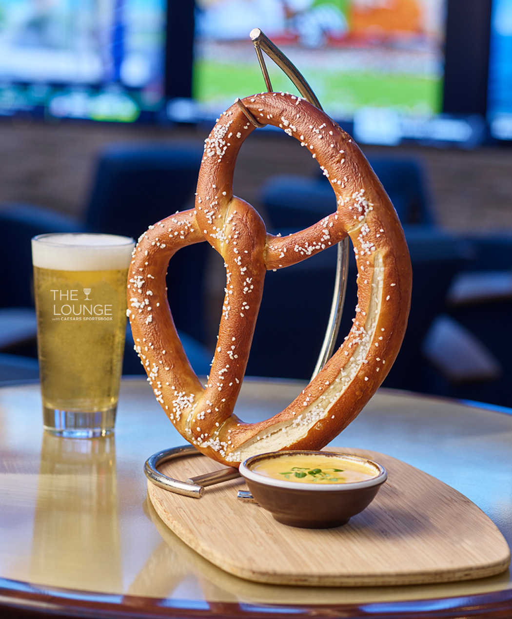 large pretzel with cheese and a pint glass of beer at the lounge with caesars sports