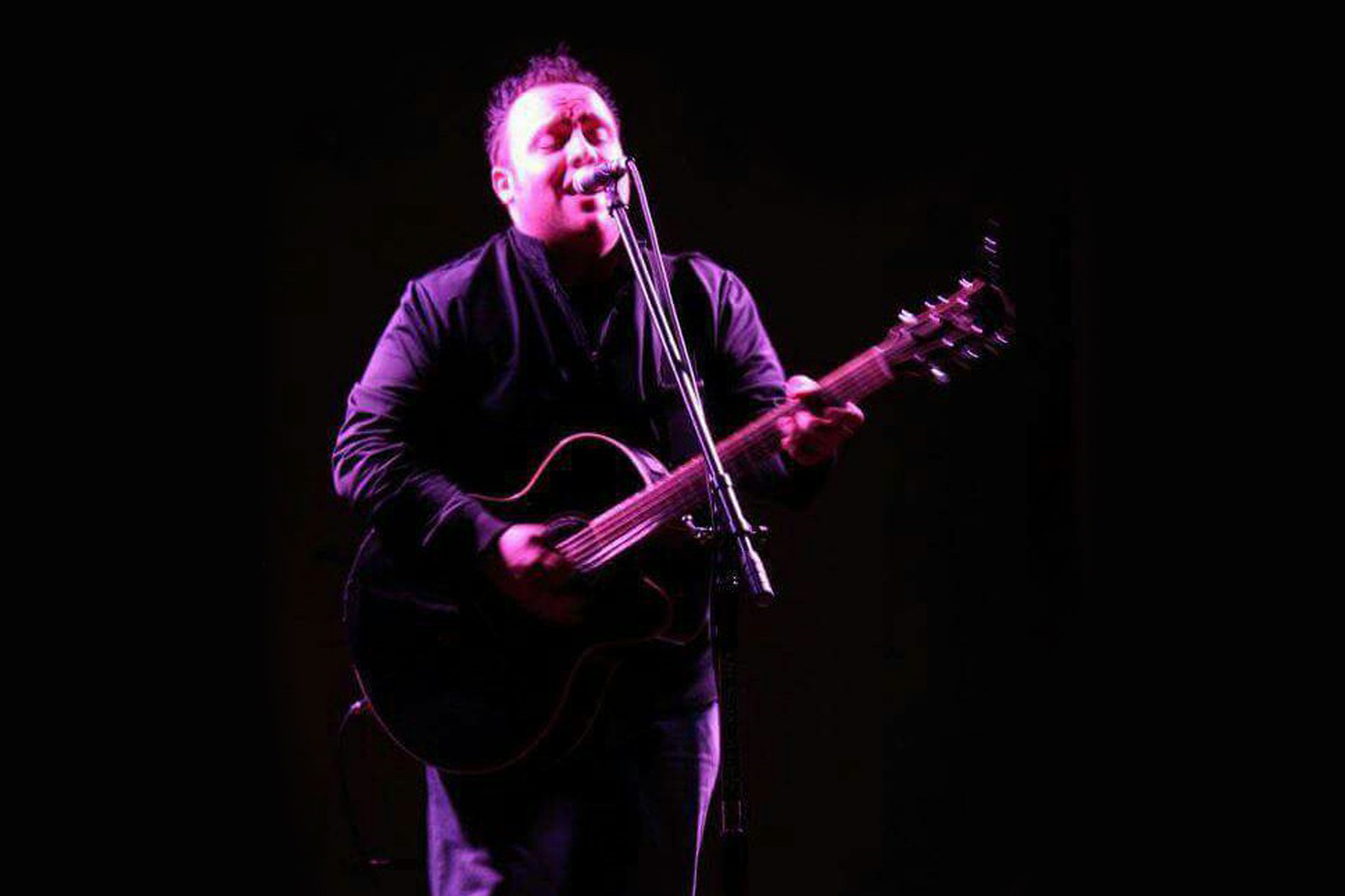 gary johnson performing at microphone with a guitar color